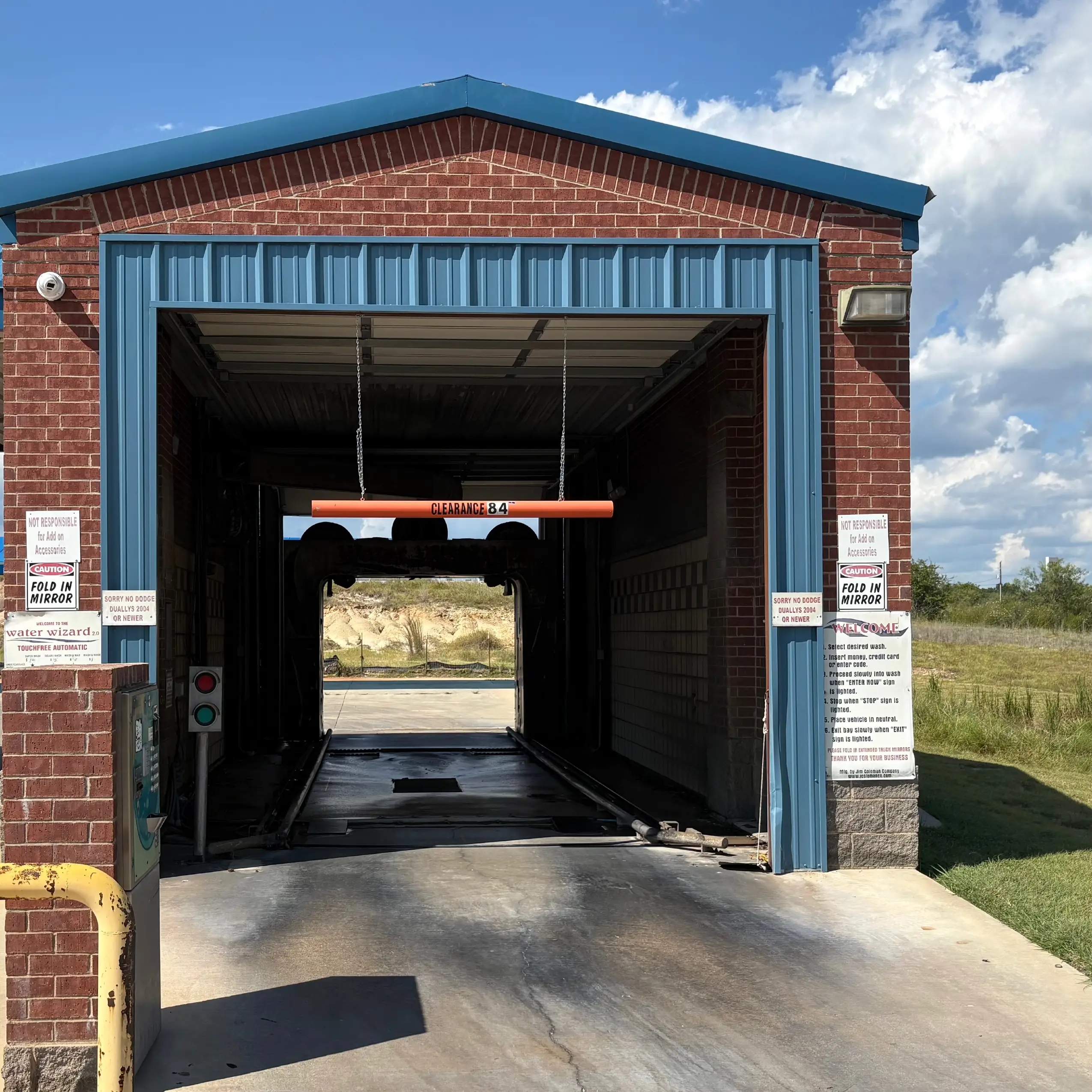 Empty car wash bay under a blue sky.